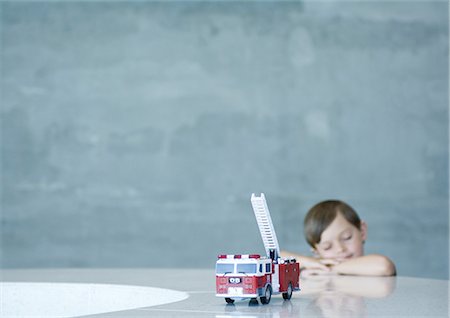 Boy dreaming behind toy firetruck Stock Photo - Premium Royalty-Free, Code: 695-03373941