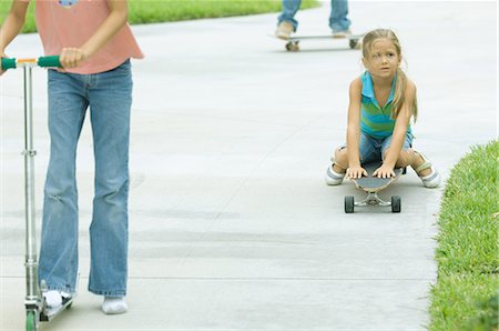 patinador en línea (hombre y mujer) - Kids riding scooters and skateboards in driveway Foto de stock - Sin royalties Premium, Código: 695-03373962