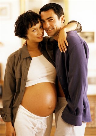 simsearch:632-01140106,k - Pregnant woman standing with arm around man's shoulders, portrait Stock Photo - Premium Royalty-Free, Code: 695-03384011
