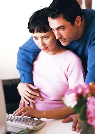 simsearch:632-01140106,k - Pregnant woman using computer, man with arms around her looking over her shoulder Stock Photo - Premium Royalty-Free, Code: 695-03384029