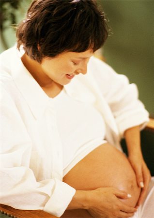 short haired women pregnant - Femme enceinte avec les mains sur le ventre, regardant vers le bas Photographie de stock - Premium Libres de Droits, Code: 695-03384053