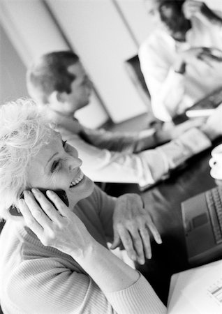 simsearch:695-05769173,k - Femme d'affaires à l'aide de téléphone portable dans la salle de conférence, collègues en arrière-plan flou, B&W Photographie de stock - Premium Libres de Droits, Code: 695-03384082