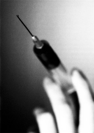 Hand holding syringe, close-up, B&W Stock Photo - Premium Royalty-Free, Code: 695-03384302