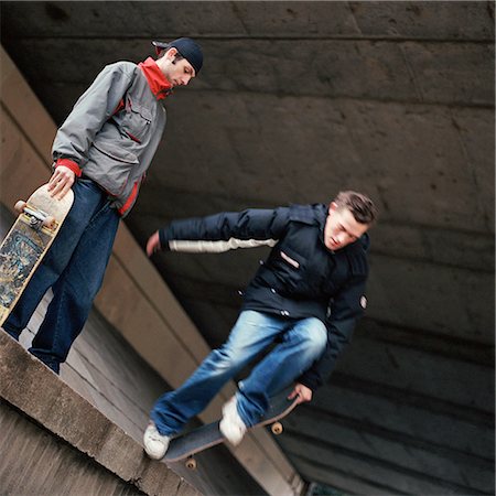 skate stunts - Two teenagers with skateboards, one jumping down from a wall Stock Photo - Premium Royalty-Free, Code: 695-03384731