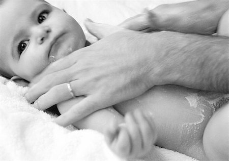 simsearch:632-01136584,k - Les mains de l'homme à friction en poudre pour bébés sur le torse du bébé, gros plan, b&w Photographie de stock - Premium Libres de Droits, Code: 695-03384916