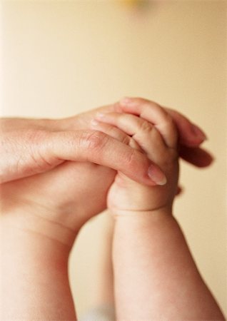 simsearch:632-03630087,k - Adult hand holding baby's hand and foot, close-up Foto de stock - Sin royalties Premium, Código: 695-03384944