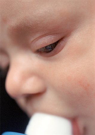 Baby with bottle in mouth, extreme close-up Stock Photo - Premium Royalty-Free, Code: 695-03384973