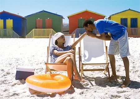 Woman sitting on beach, man kissing her hand Stock Photo - Premium Royalty-Free, Code: 695-03385181