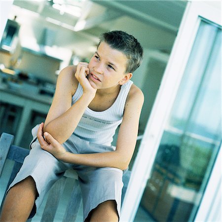 Teenage boy sitting with hand under chin Stock Photo - Premium Royalty-Free, Code: 695-03385275