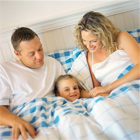 eiderdown duvet white - Girl lying in bed between parents Stock Photo - Premium Royalty-Free, Code: 695-03385351
