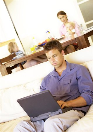 family eating computer - Woman and children at table, man using laptop on sofa Stock Photo - Premium Royalty-Free, Code: 695-03385370