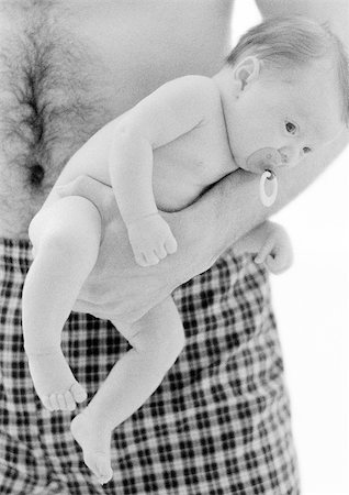 father holding a baby in his hands - Father holding infant with pacifier in mouth, b&w Stock Photo - Premium Royalty-Free, Code: 695-03385503
