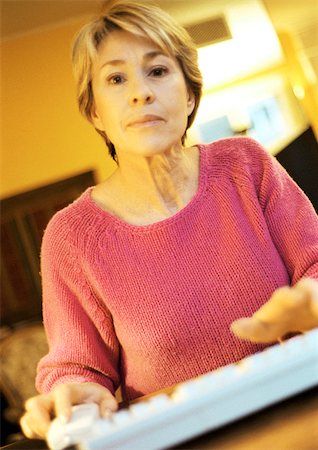Mature woman, hands on computer keyboard, looking into camera, portrait. Stock Photo - Premium Royalty-Free, Code: 695-03385582
