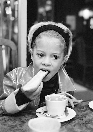 Girl eating bread, drinking hot chocolate, b&w. Stock Photo - Premium Royalty-Free, Code: 695-03385625