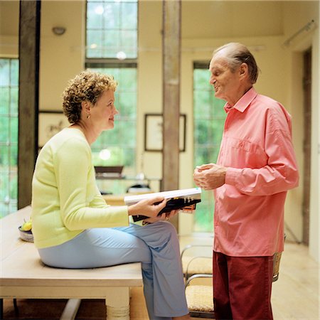 Mature couple face to face, woman sitting on table, man standing, side view Stock Photo - Premium Royalty-Free, Code: 695-03385996