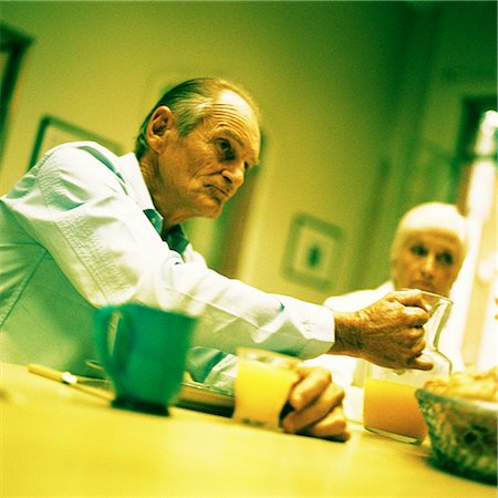 elderly doubt - Mature couple sitting at table, man holding pitcher Stock Photo - Premium Royalty-Free, Code: 695-03385999