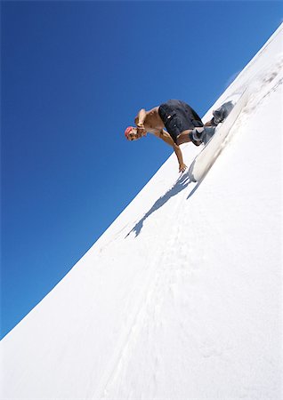 sliding - Man snowboarding down slope, low angle view. Stock Photo - Premium Royalty-Free, Code: 695-03386169