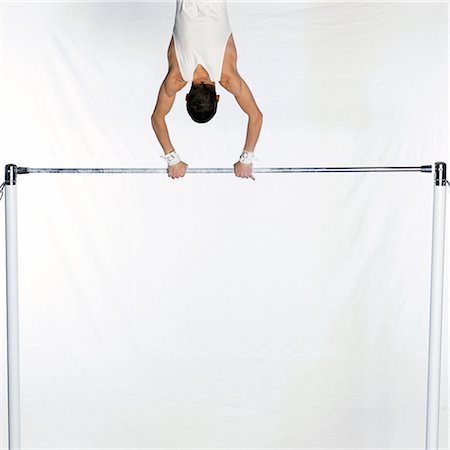 simsearch:695-03383548,k - Male gymnast swinging on horizontal bar, rear view, cropped Fotografie stock - Premium Royalty-Free, Codice: 695-03386255