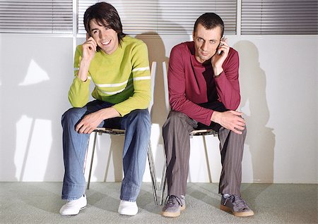smiling and sulking - Two men in seats with cell phones Stock Photo - Premium Royalty-Free, Code: 695-03386487