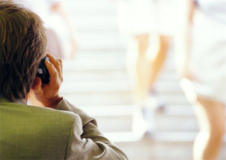 Businessman using cell phone, rear view, blurred Stock Photo - Premium Royalty-Free, Code: 695-03386809