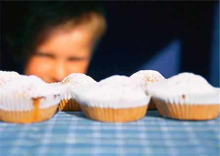 simsearch:633-02128716,k - Kind betrachten Muffins aufgereiht auf Tisch, Tiefenschärfe Stockbilder - Premium RF Lizenzfrei, Bildnummer: 695-03387020
