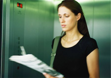 Woman reading newspaper in elevator Stock Photo - Premium Royalty-Free, Code: 695-03387150