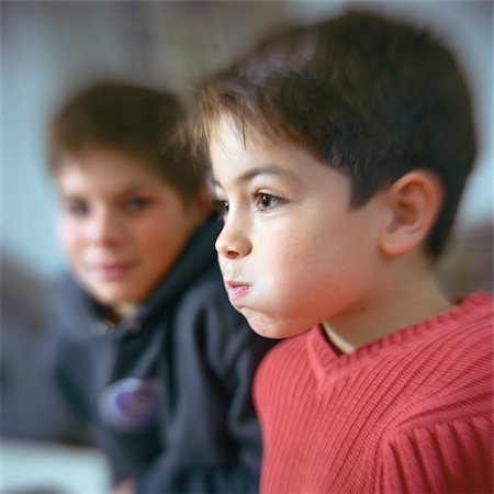 Boy puffing cheeks out, second boy looking at him in background Stock Photo - Premium Royalty-Free, Code: 695-03387281