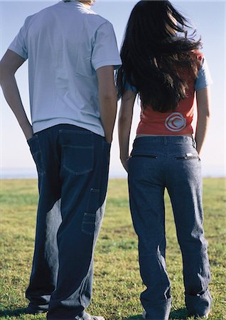 Young couple standing together on grass gazing at horizon over water in distance Foto de stock - Sin royalties Premium, Código: 695-03387517