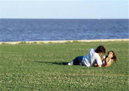 simsearch:632-01150072,k - Young couple laying together on grass by water, blurred Stock Photo - Premium Royalty-Free, Code: 695-03387510
