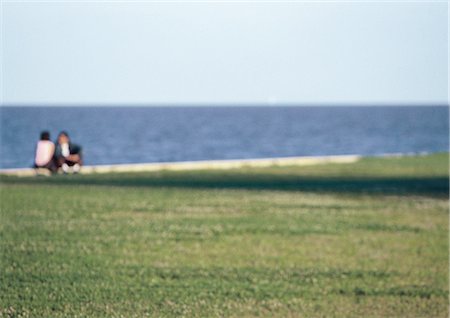 Young couple sitting on seawall, blurred Stock Photo - Premium Royalty-Free, Code: 695-03387511
