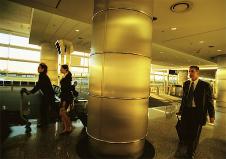 running suitcase - Business people walking in airport terminal. Stock Photo - Premium Royalty-Free, Code: 695-03387542