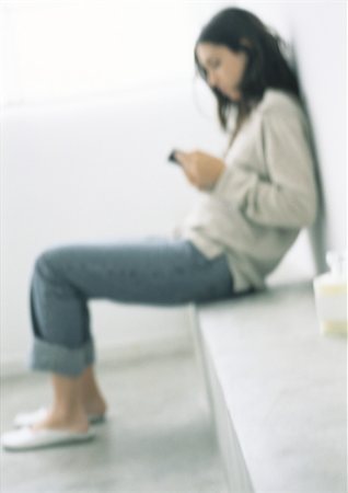 slippers women - Woman sitting, leaning against wall, side view, blurred Stock Photo - Premium Royalty-Free, Code: 695-03387575