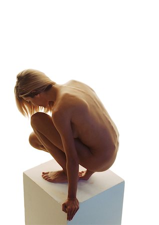 Nude woman with head down crouching on pedestal, side view Stock Photo - Premium Royalty-Free, Code: 695-03387775