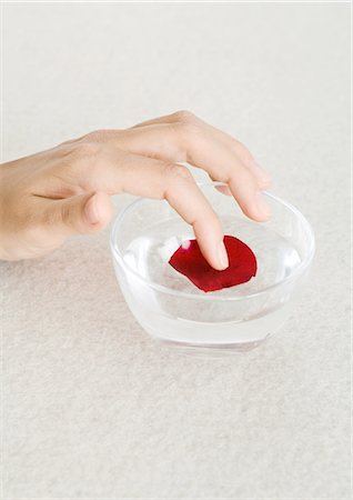 Woman's hand touching rose petal in bowl of water Stock Photo - Premium Royalty-Free, Code: 695-03388263