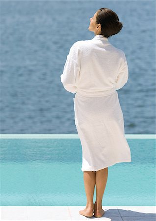 Woman in bathrobe standing near pool overlooking sea, rear view Stock Photo - Premium Royalty-Free, Code: 695-03388413