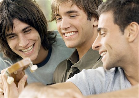 Three young male friends, looking at guitar Stock Photo - Premium Royalty-Free, Code: 695-03388532