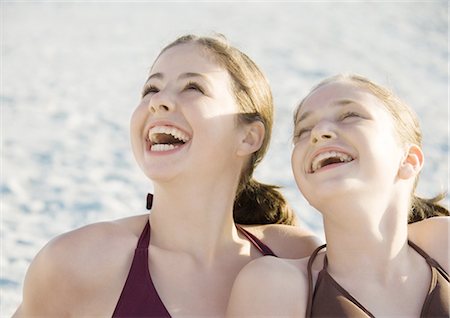 preteen swim suit models - Two preteen girls laughing and looking up on beach Stock Photo - Premium Royalty-Free, Code: 695-03388639