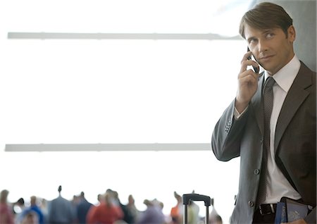 Businessman using cell phone in airport Stock Photo - Premium Royalty-Free, Code: 695-03388698