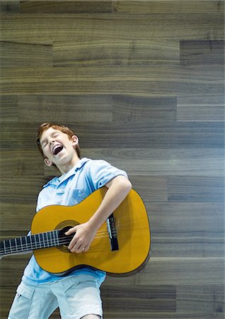 Boy playing guitar and singing with emotion Stock Photo - Premium Royalty-Free, Code: 695-03388771