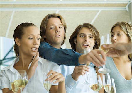 disruption - Man reaching over friends' shoulders for glass of champagne Stock Photo - Premium Royalty-Free, Code: 695-03388819