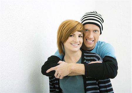 funky young couple studio - Young couple, man standing behind woman with arms around her, both smiling at camera Stock Photo - Premium Royalty-Free, Code: 695-03388936