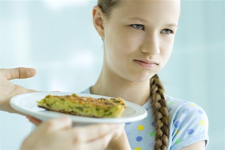 reject food - Hands holding up slice of quiche toward girl, girl making face and looking away Stock Photo - Premium Royalty-Free, Code: 695-03389117