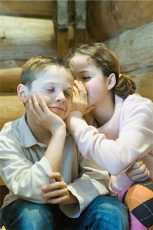 sister whispering sister - Girl whispering in boy's ear, boy closing eyes, smiling Stock Photo - Premium Royalty-Free, Code: 695-03389359