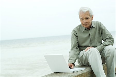 simsearch:633-01713826,k - Senior man sitting on low wall, using laptop computer, looking at camera Stock Photo - Premium Royalty-Free, Code: 695-03389515