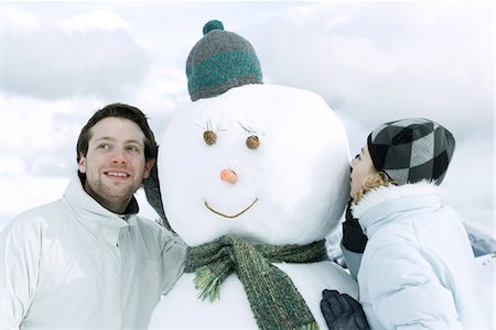 simsearch:695-05766599,k - Deux jeunes amis sur l'autre côté du bonhomme de neige, un chuchotement, l'écoute Photographie de stock - Premium Libres de Droits, Code: 695-03389549