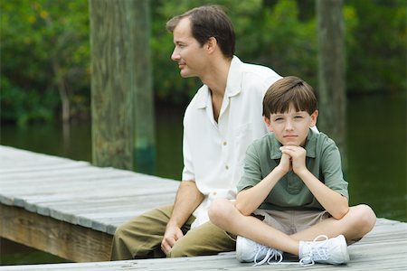 simsearch:632-01380362,k - Boy sitting on dock with father, smiling at camera Foto de stock - Royalty Free Premium, Número: 695-03389603