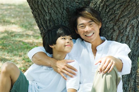 Father and son under tree together, man smiling at camera Stock Photo - Premium Royalty-Free, Code: 695-03389638