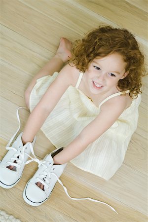 simsearch:695-05768252,k - Little girl on floor with hands in shoes, smiling, view from directly above Fotografie stock - Premium Royalty-Free, Codice: 695-03389677