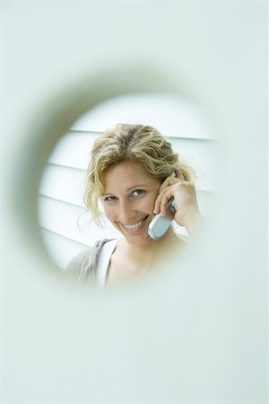 framing face - Woman using cell phone, framed by hole Stock Photo - Premium Royalty-Free, Code: 695-03389683