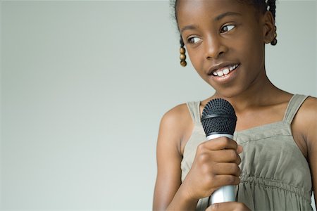 Girl holding up microphone, looking away, close-up Stock Photo - Premium Royalty-Free, Code: 695-03389729